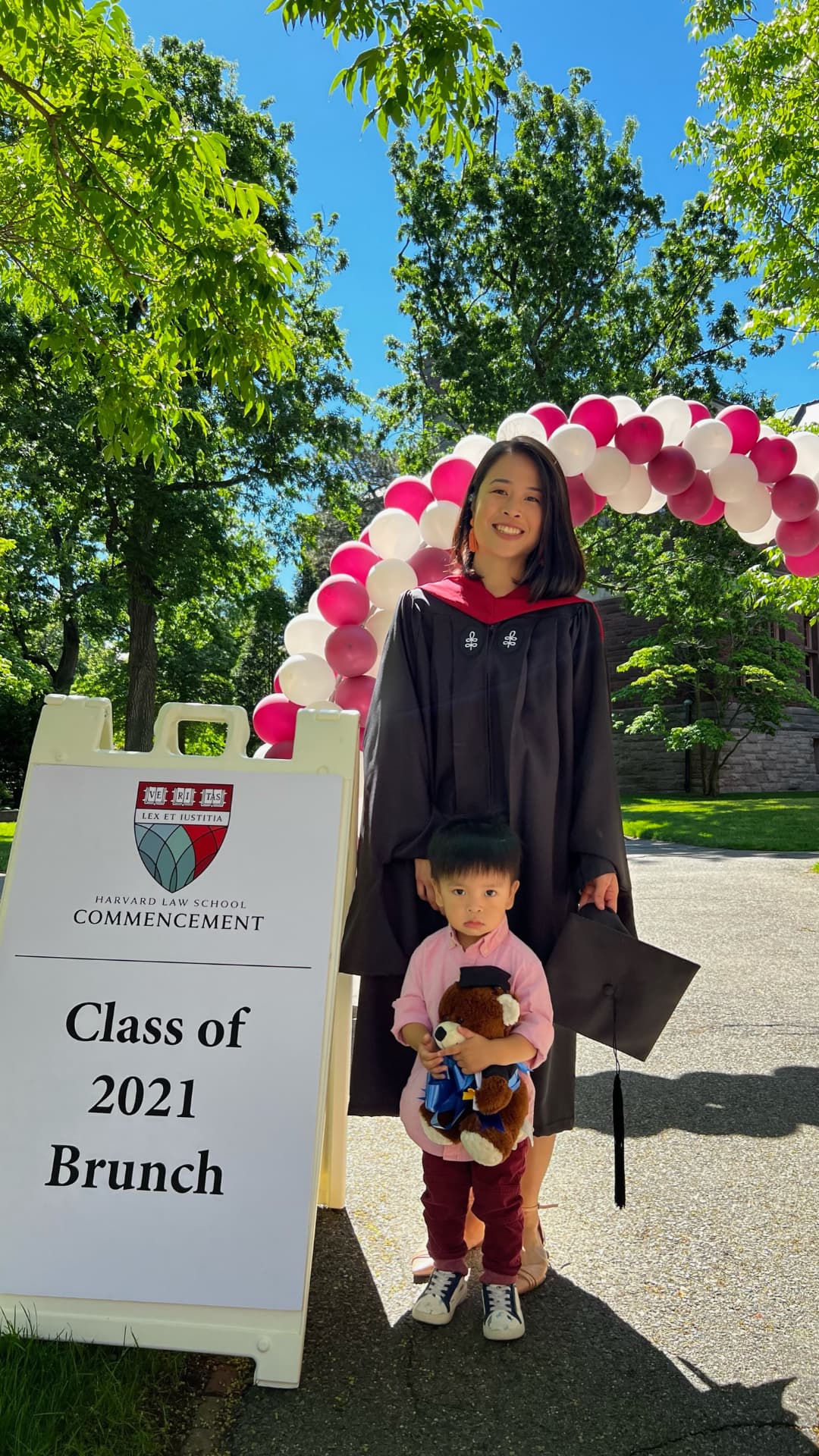 Jocelyn and her son under the pink and white balloon arch at the commencement brunch