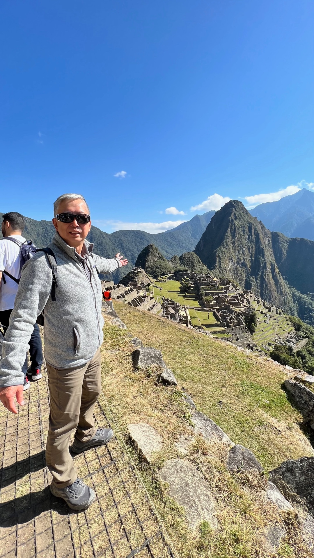 Ken gesturing toward Machu Picchu with Huayna Picchu behind him