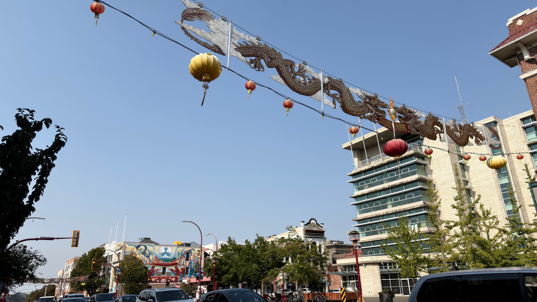 Dragon decorations and red and gold lanterns hanging above a Victoria Chinatown street