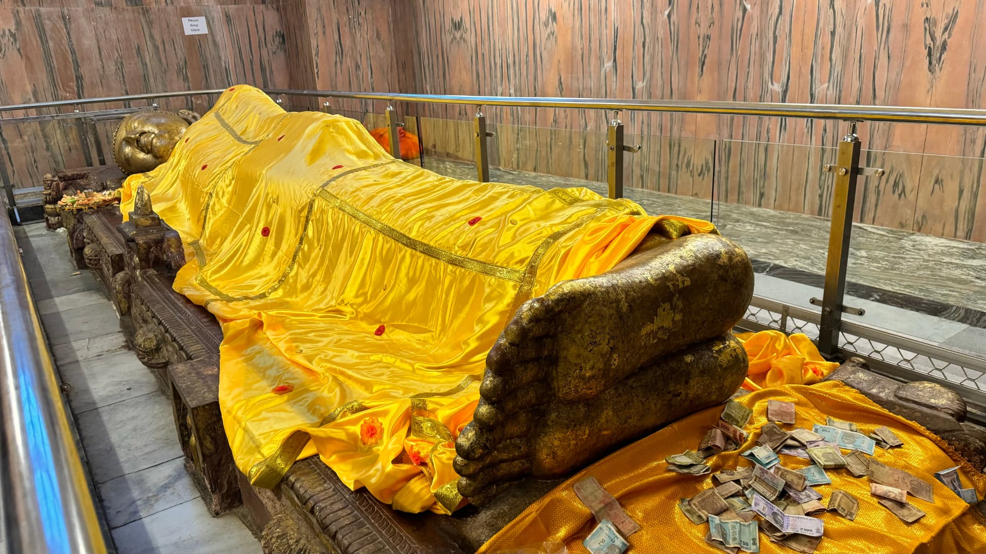 The reclining Buddha draped in yellow cloth inside the Nirvana Temple. — Kushinagar, Uttar Pradesh, India.