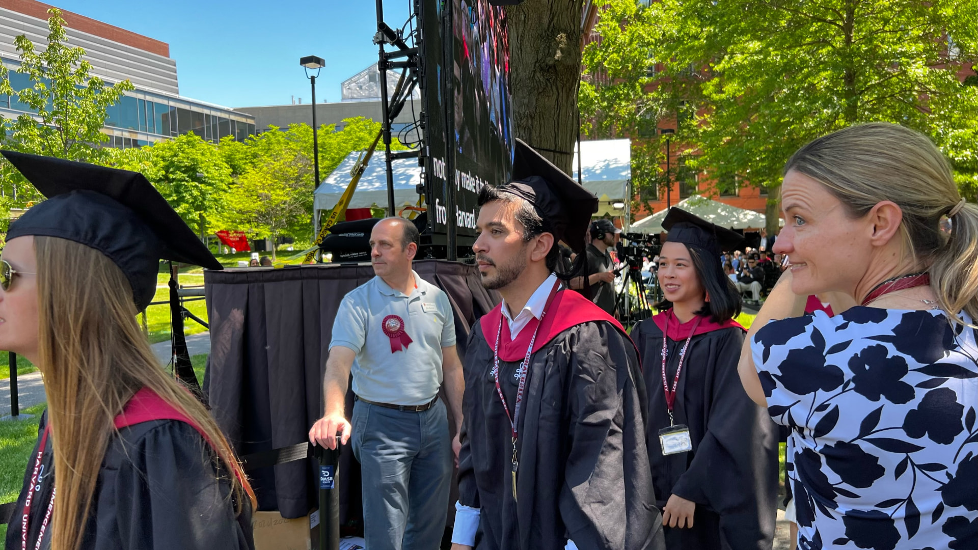 Graduates gathering near the stage screens, Jocelyn among them