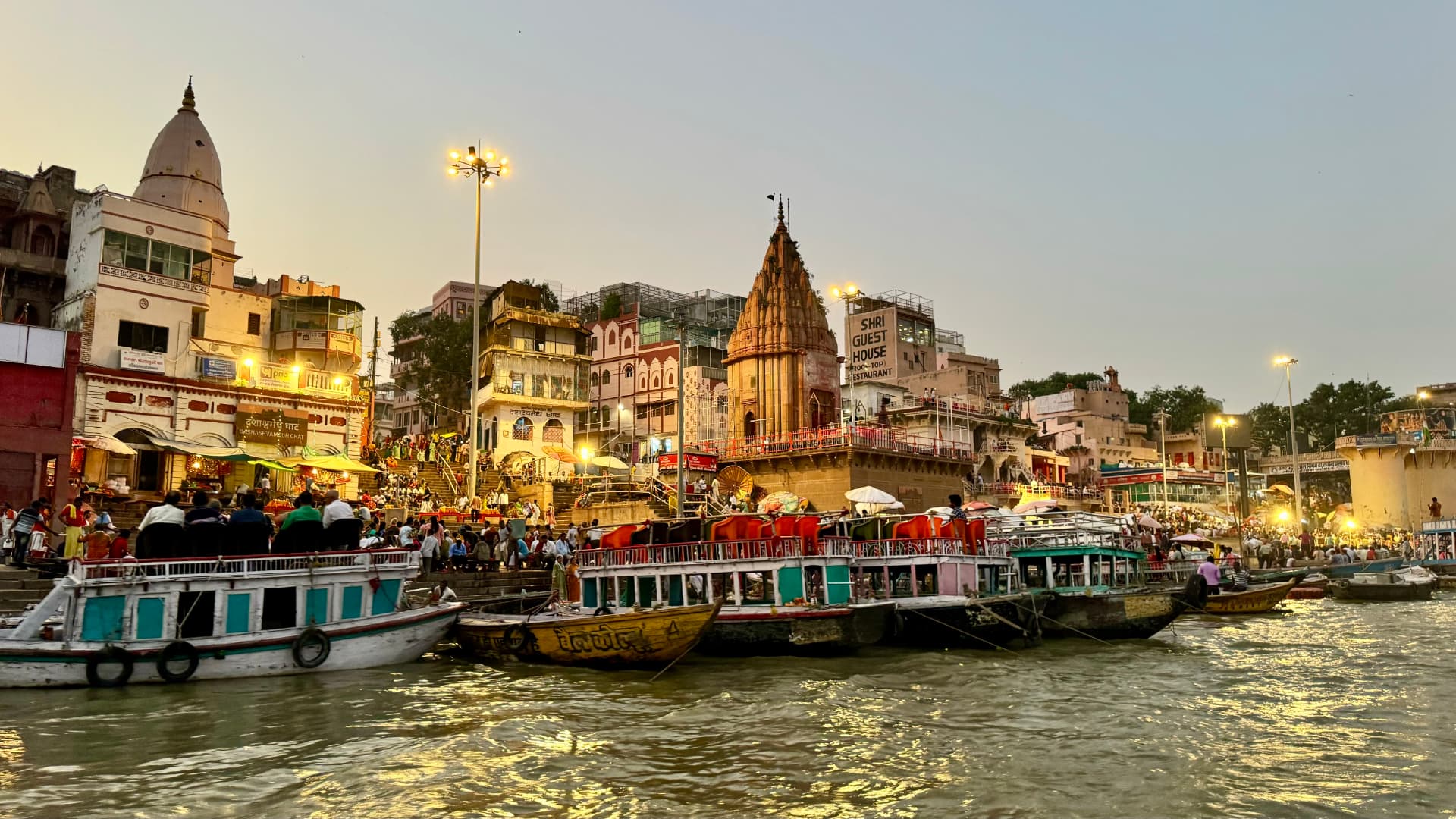 Illuminated temples and busy boats beside the evening riverfront. — Varanasi, Uttar Pradesh, India.