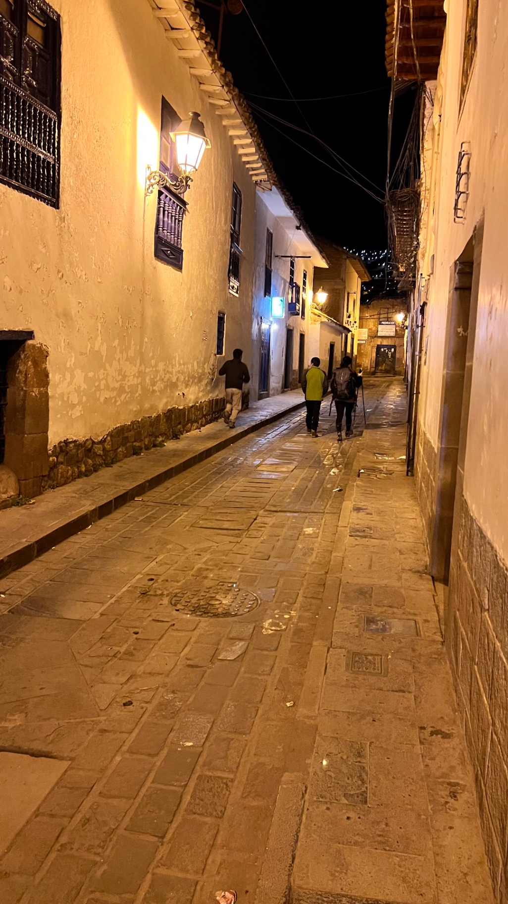 Warmly lit narrow stone lane in old Cusco