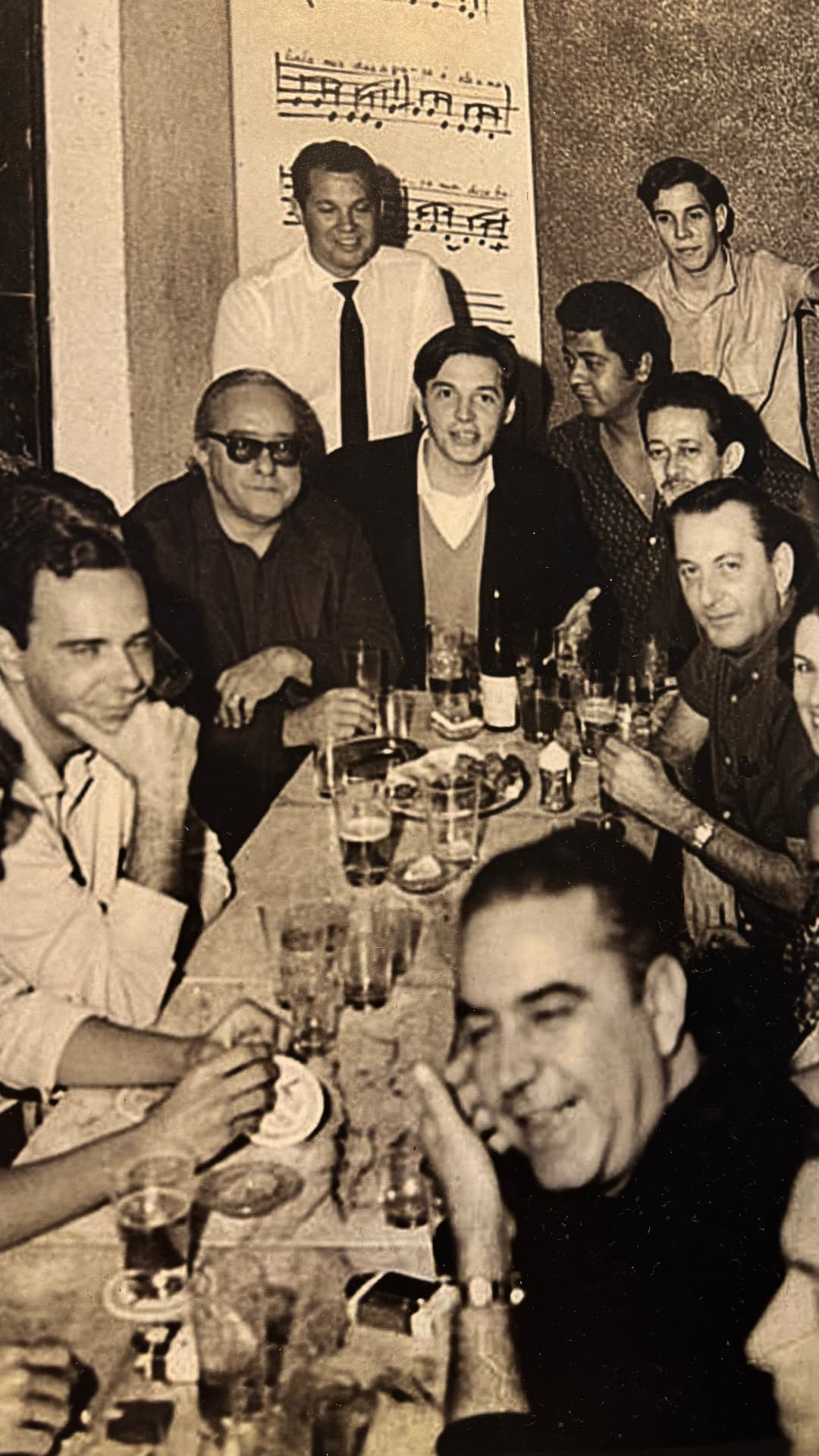 Historic black-and-white photograph of musicians and guests gathered around a table