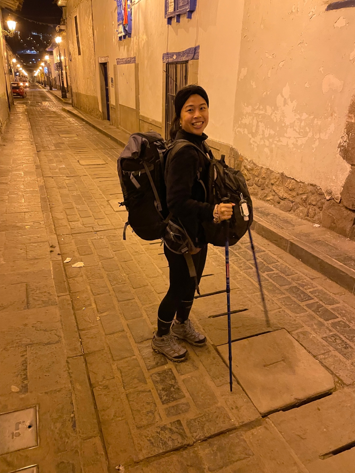 Traveller walking with a cane along a narrow Cusco street at night