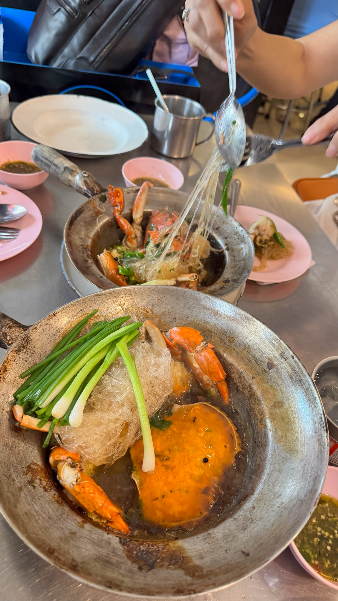 Two pans of crab and glass noodles being served