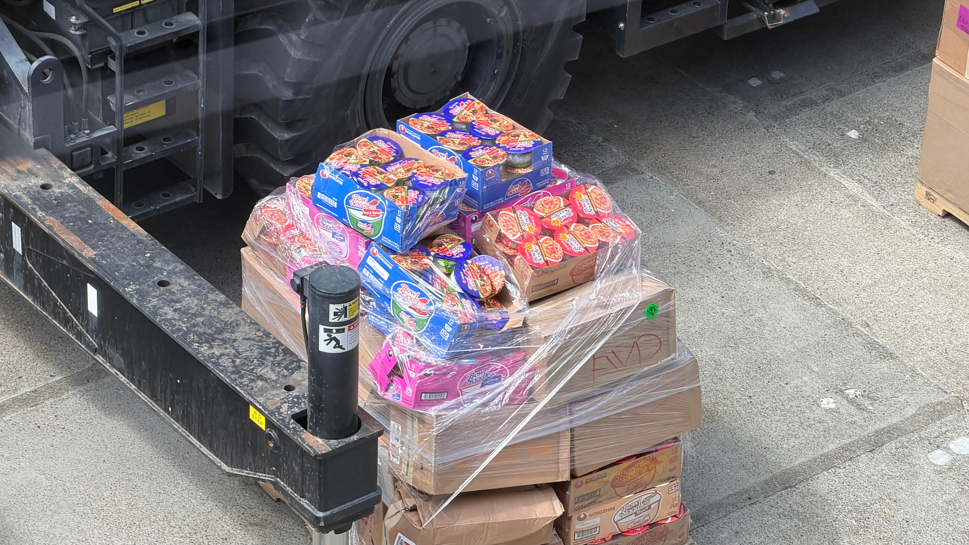 A close-up of pallets of food supplies and instant noodles wrapped in plastic film on the dock, ready to be loaded aboard