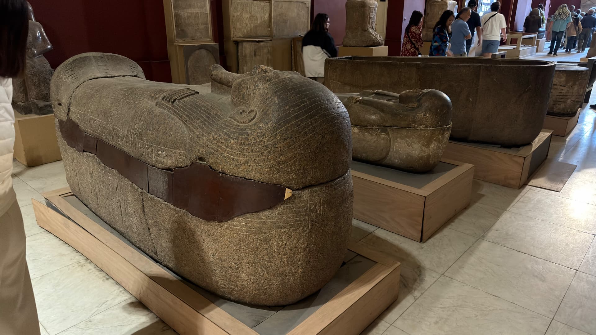 Carved granite sarcophagi resting on wooden supports in a museum hall