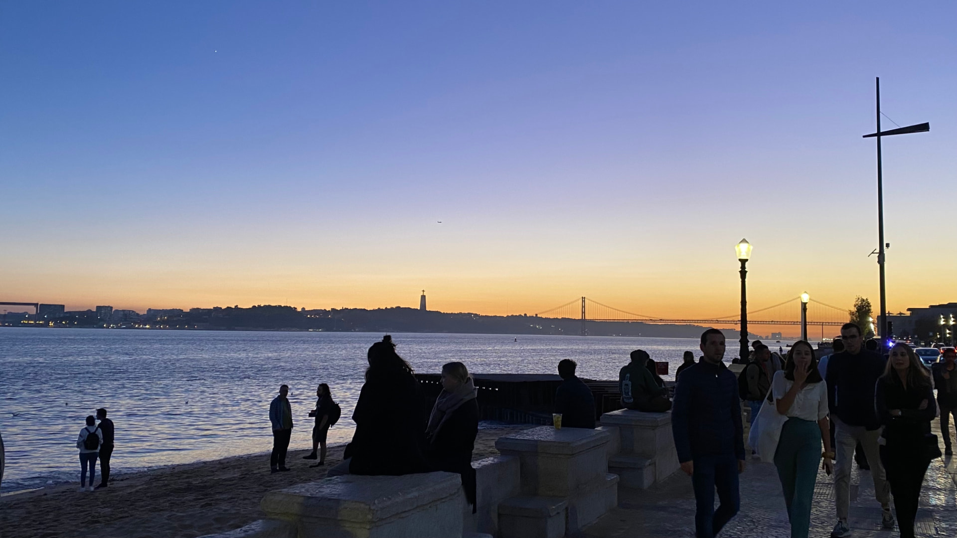 Silhouetted figures standing by the water at blue hour