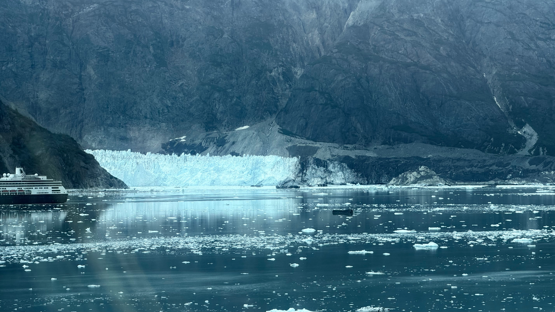 A cruise ship passing a broad blue tidewater glacier in Glacier Bay