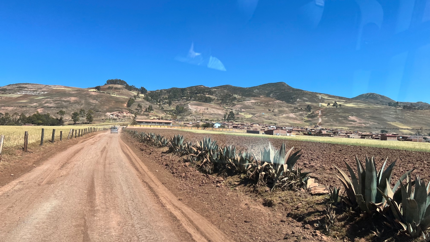Unpaved road crossing farmland beneath the snow-dusted Andes