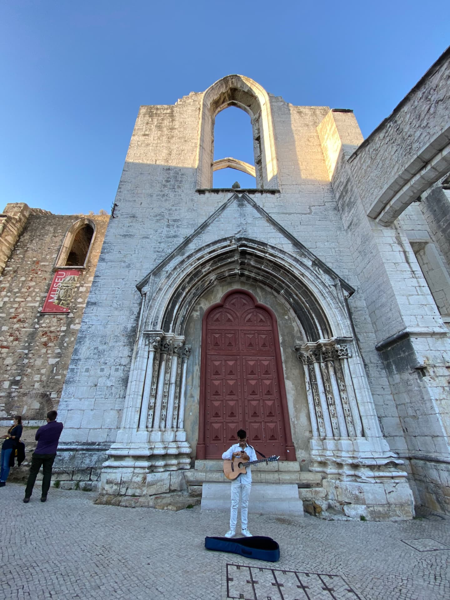The gothic entrance to Carmo Convent ruins with a musician outside