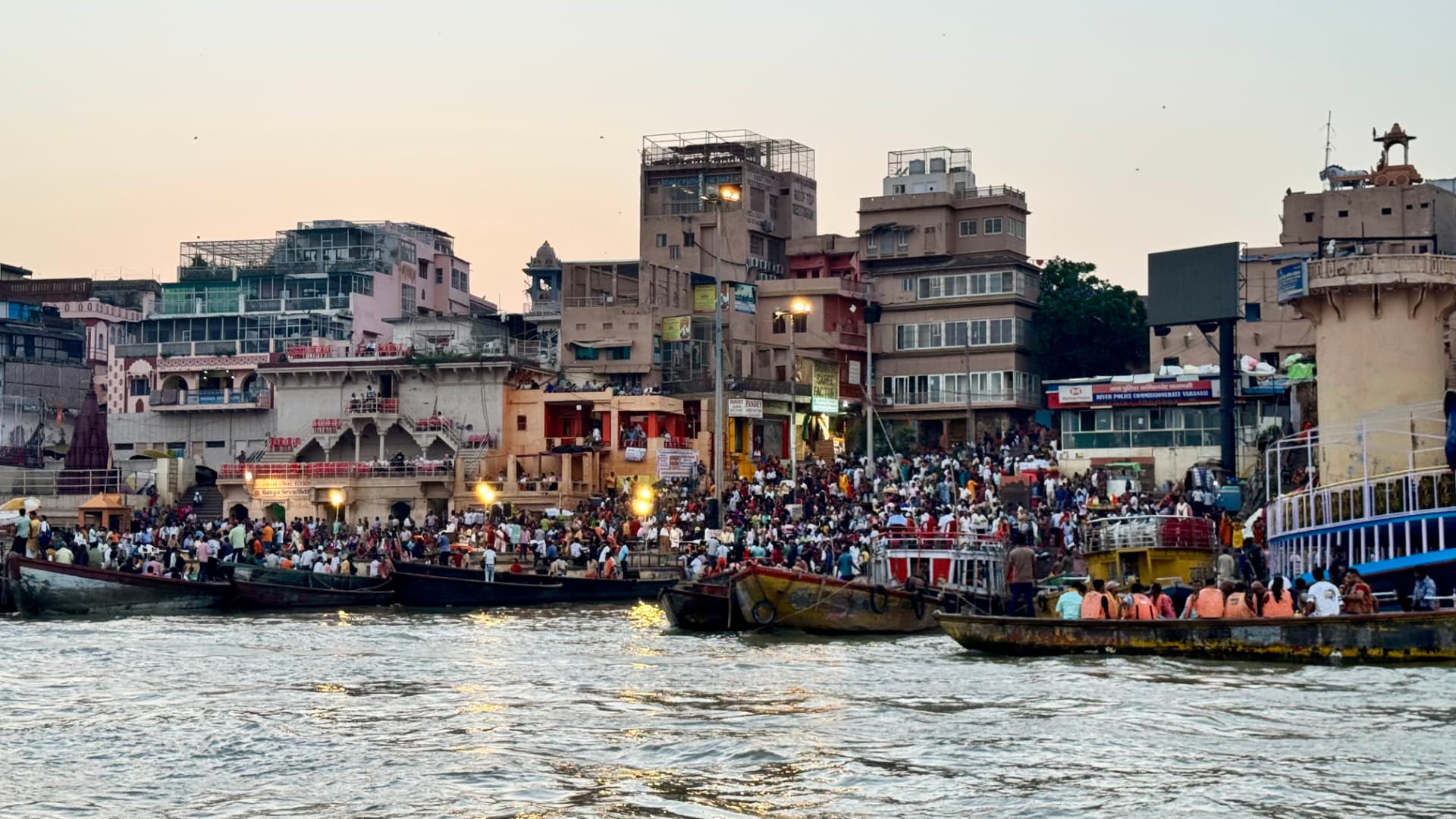 Boats and crowds gather below a densely built riverfront. — Varanasi, Uttar Pradesh, India.