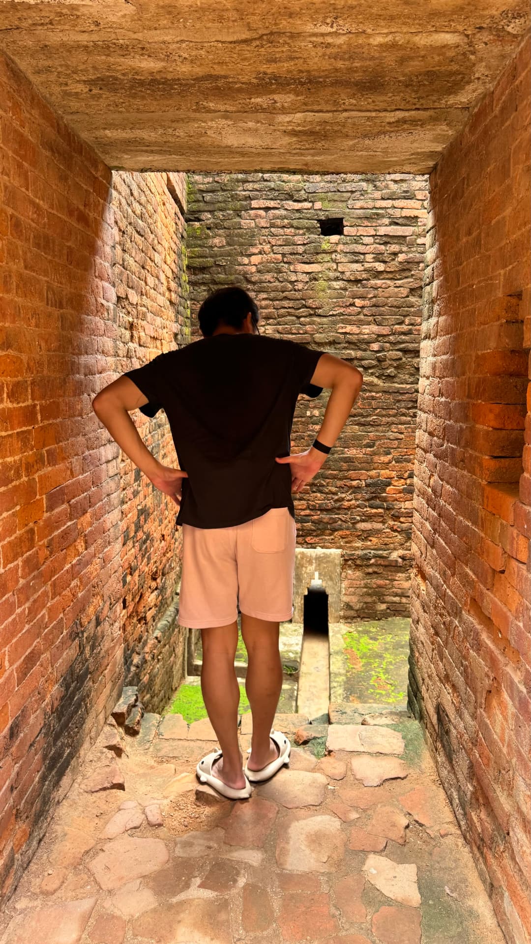 A visitor stands in a narrow passage framed by ancient brick walls. — Nalanda, Bihar, India · Patna chapter.