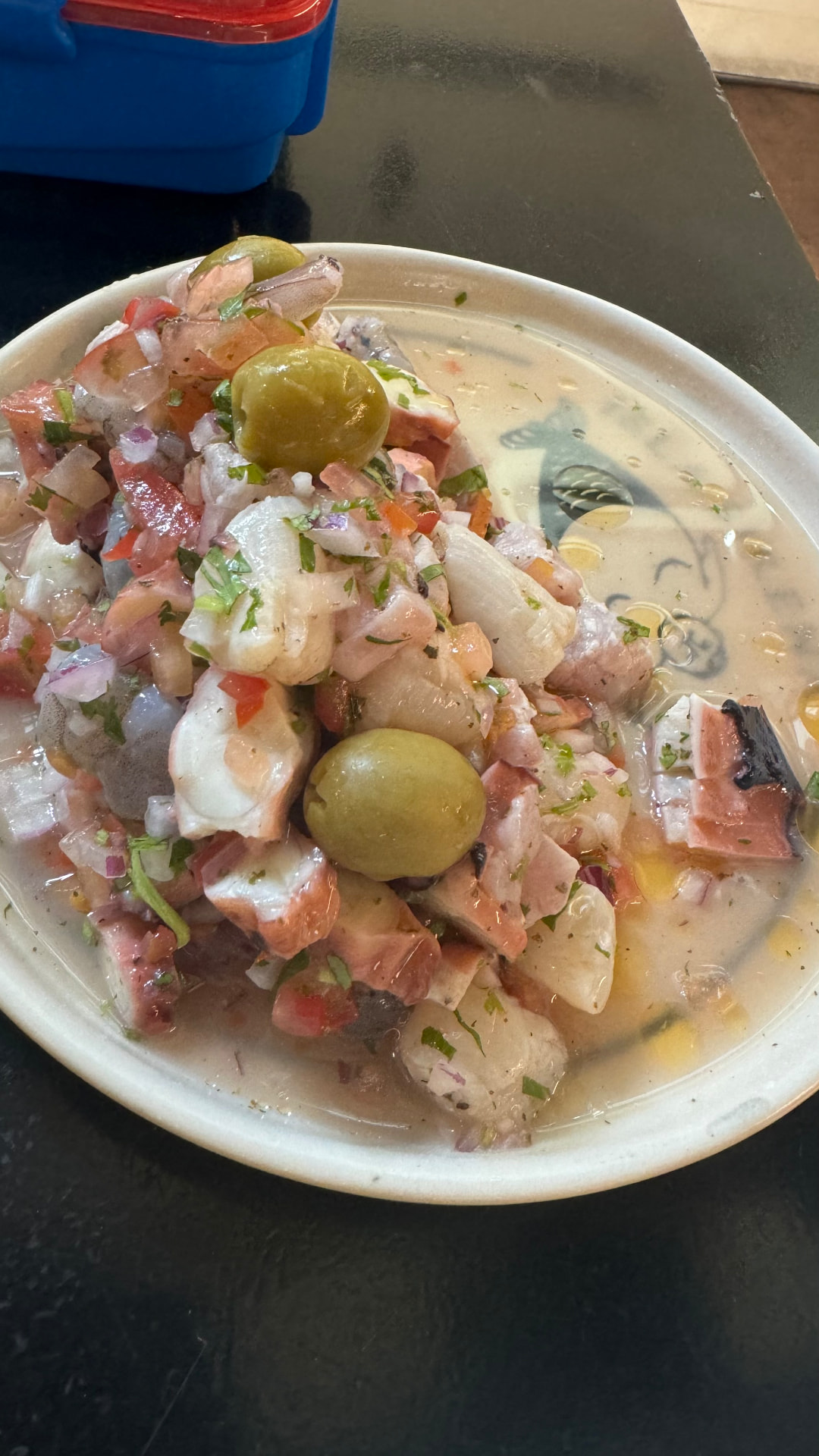 Fresh seafood ceviche with onion, tomato, herbs, and green olives