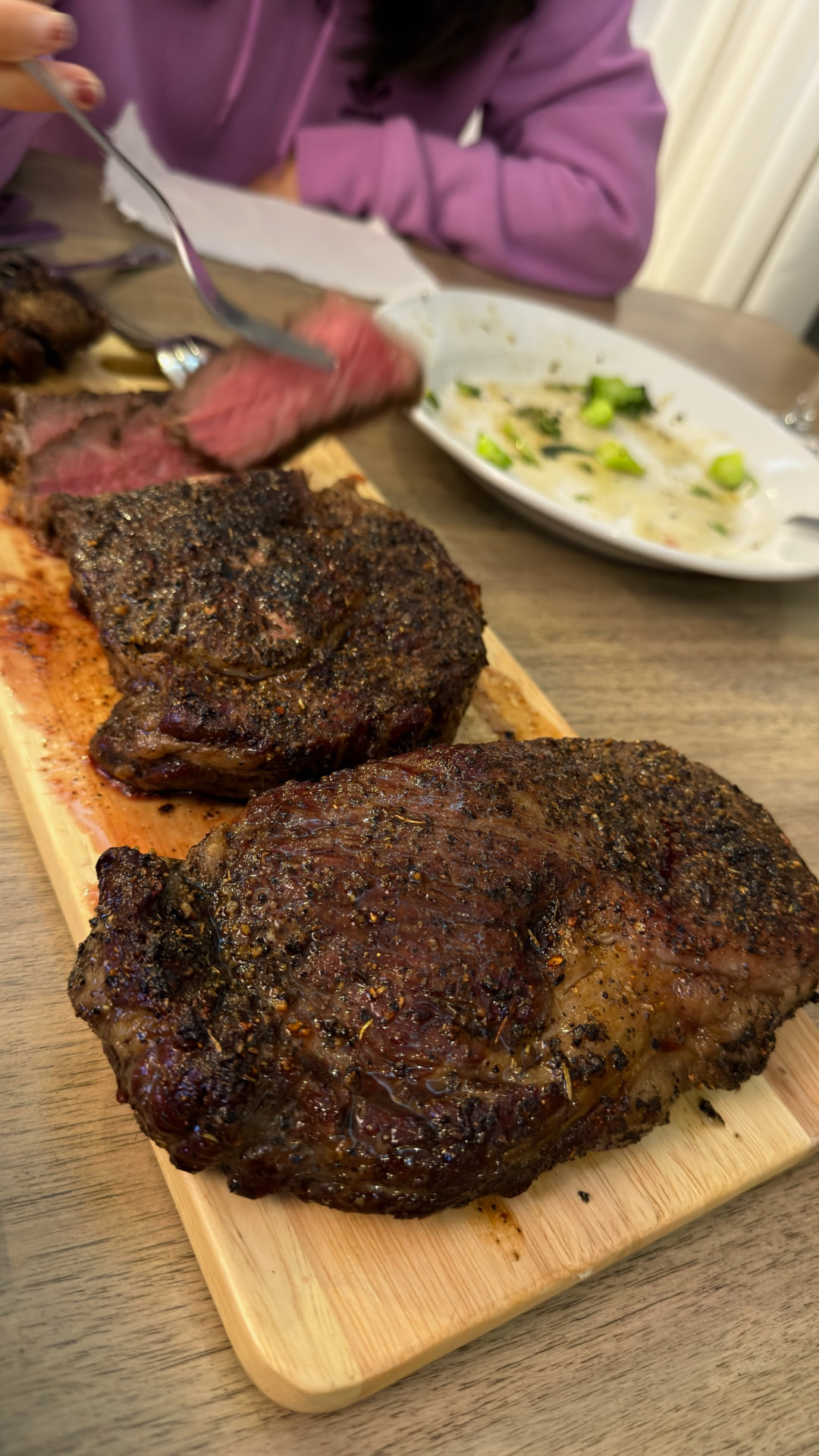 Pepper-crusted steaks being sliced at the table