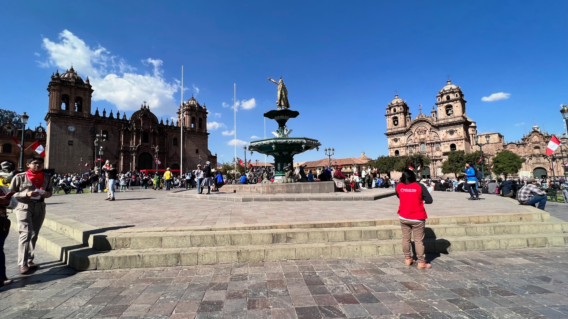 Plaza de Armas in Cusco with its fountain, cathedral, and church beneath a clear blue sky