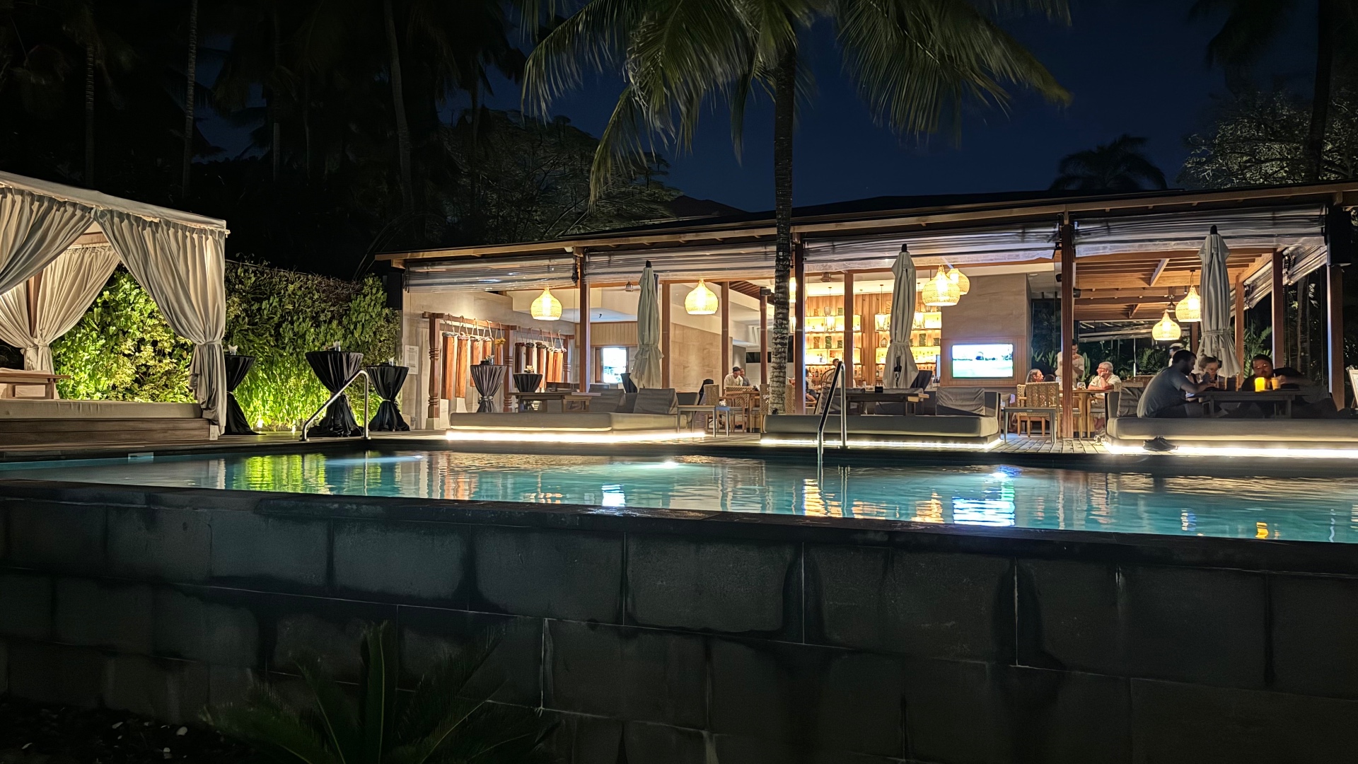 Open-air pool bar glowing beside the water at night