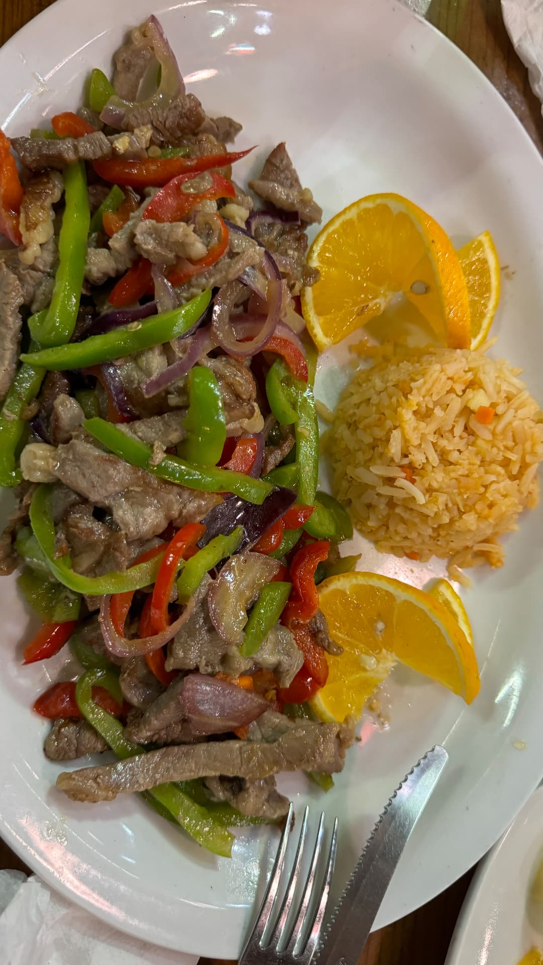 Sautéed beef with green and red peppers, onions, rice, and orange slices