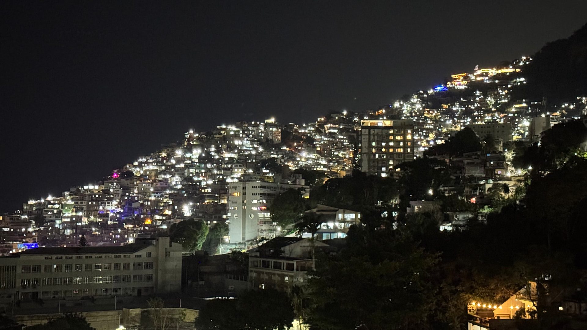 A densely built Rio de Janeiro hillside glowing with lights at night