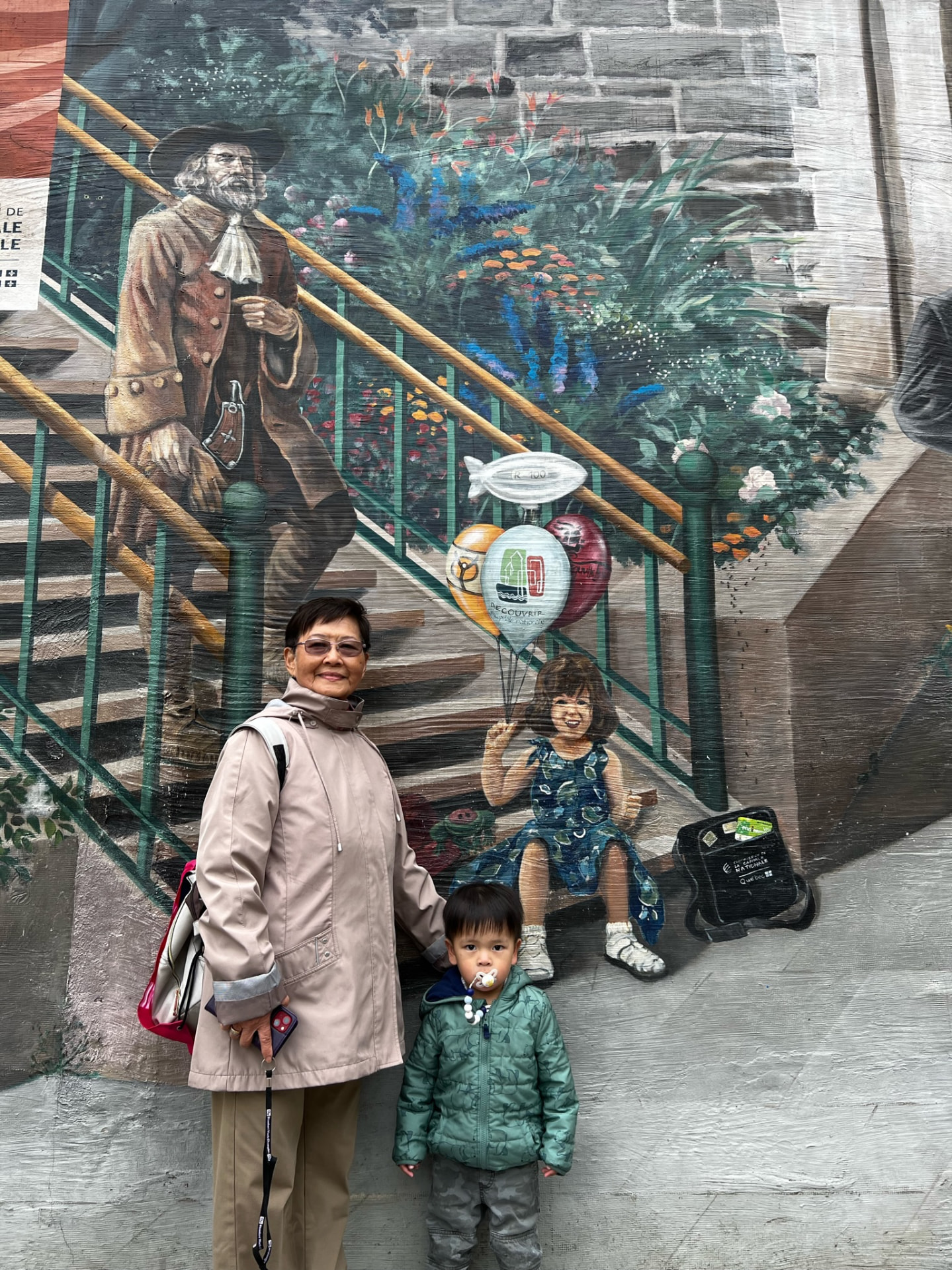Grandmother and child standing in front of the Québec City mural