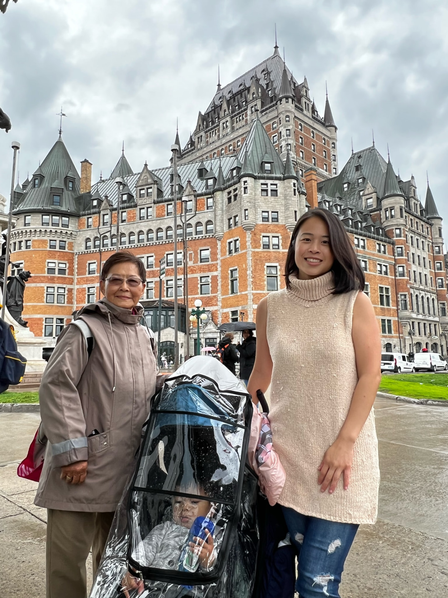 Family with a stroller standing before Château Frontenac on a rainy day