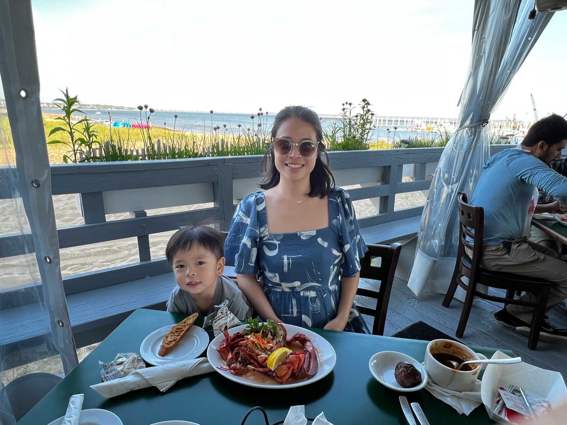 Mother and child with a lobster lunch beside the water