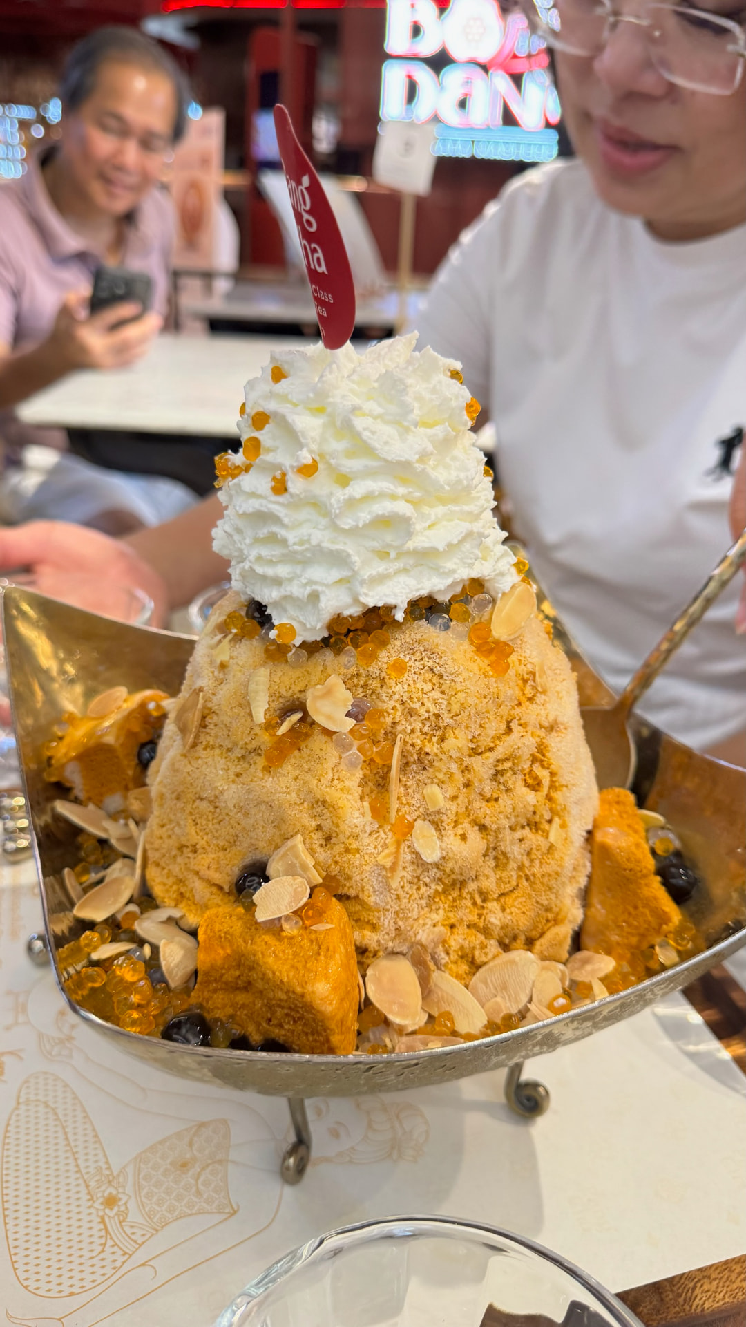 A towering Thai shaved-ice dessert topped with whipped cream