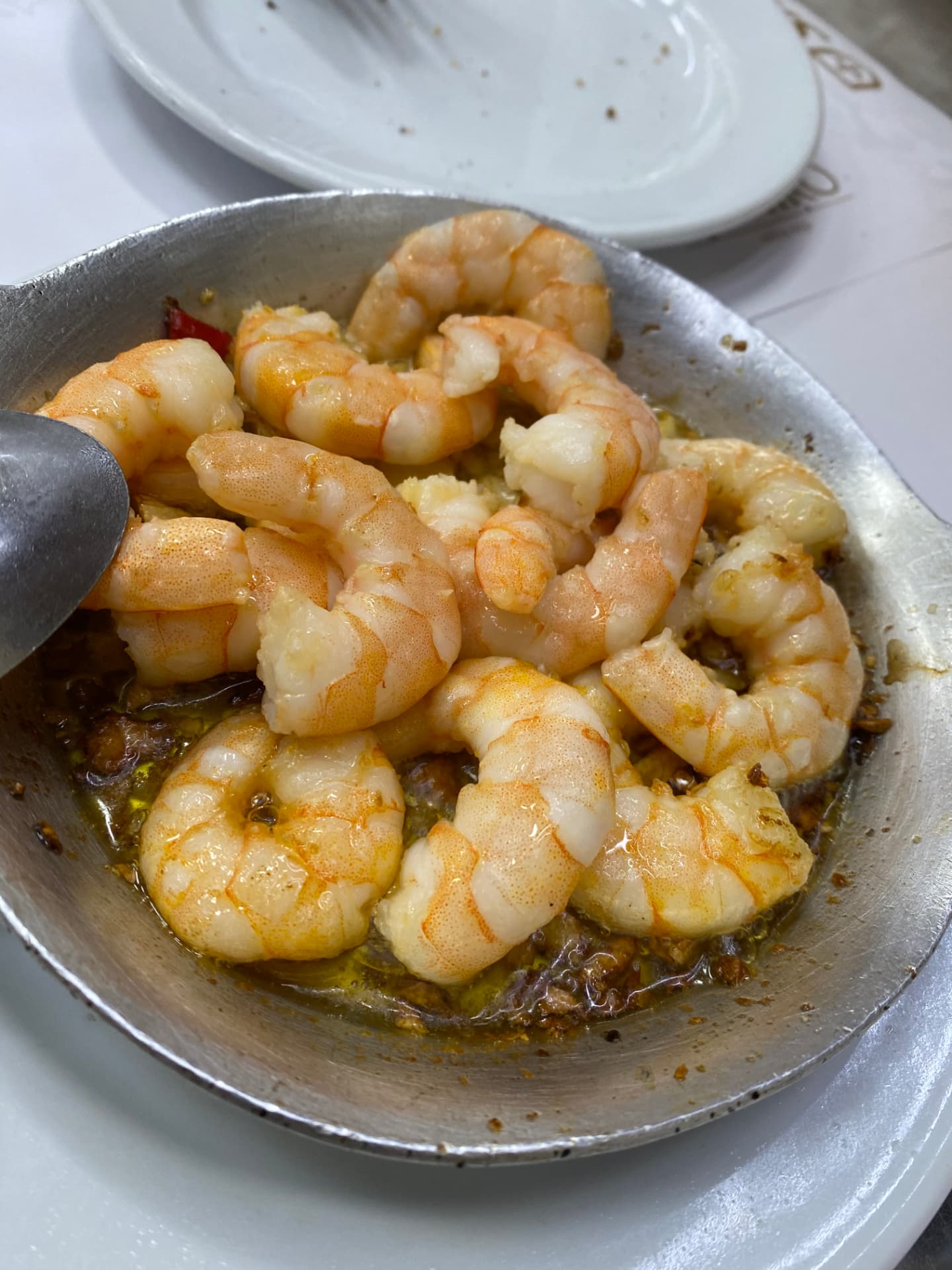 Sautéed peeled prawns served on a small metal plate