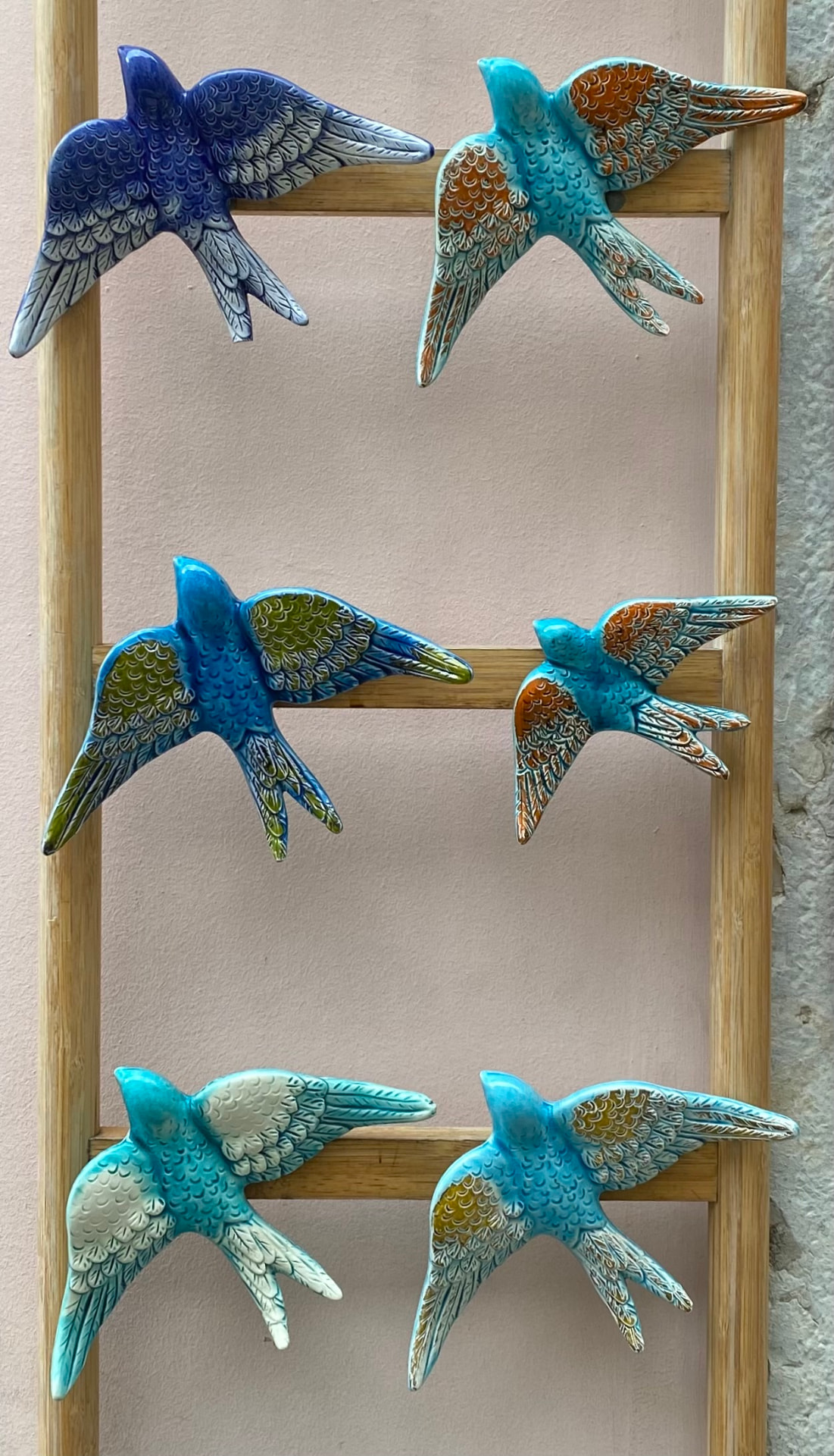 Painted ceramic swallows in blue and teal mounted on a wall