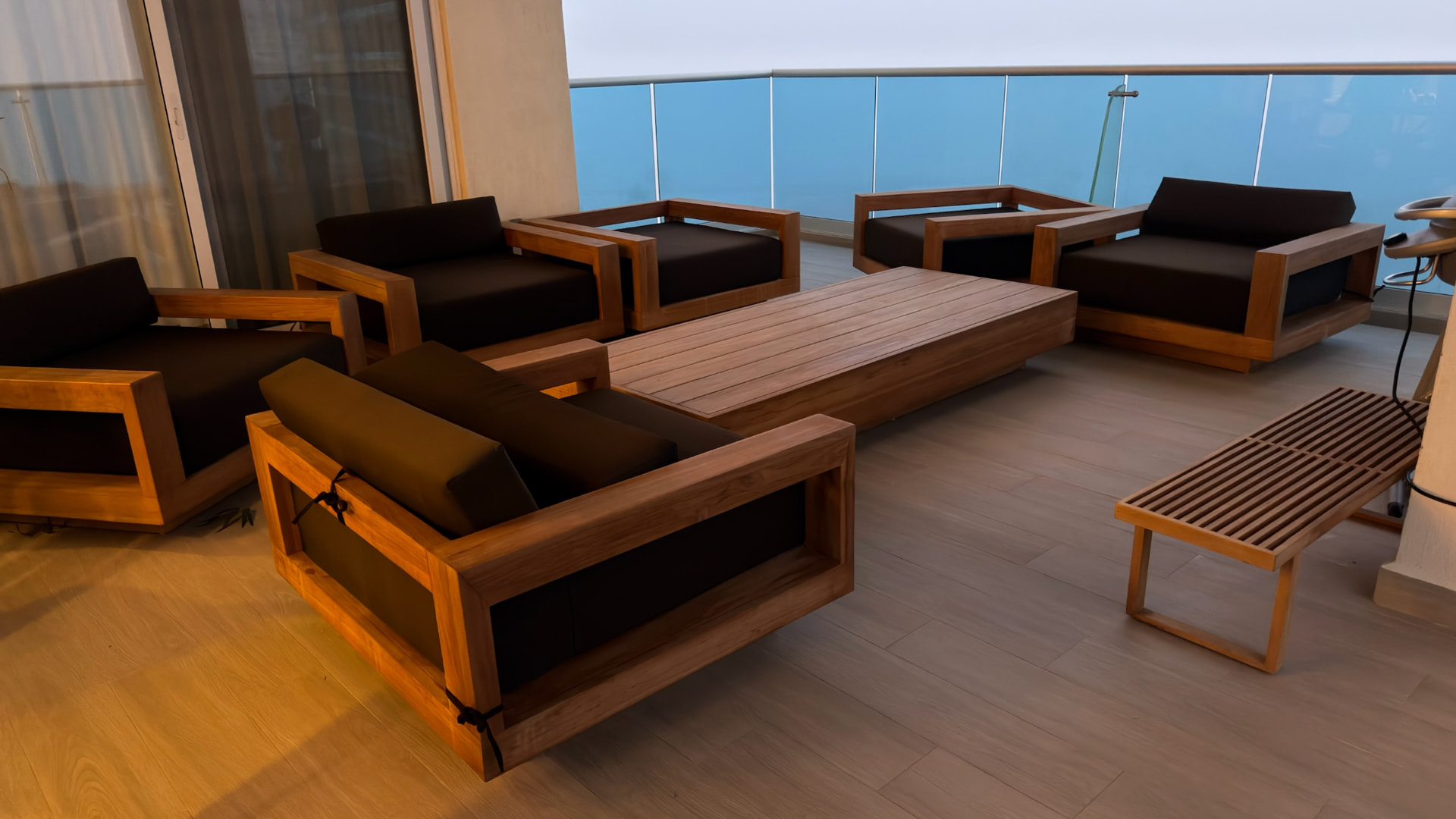 Wood-framed lounge seating gathered around a broad balcony table