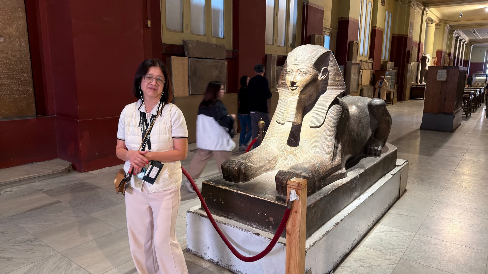 Becky standing beside a large stone sphinx in a museum gallery