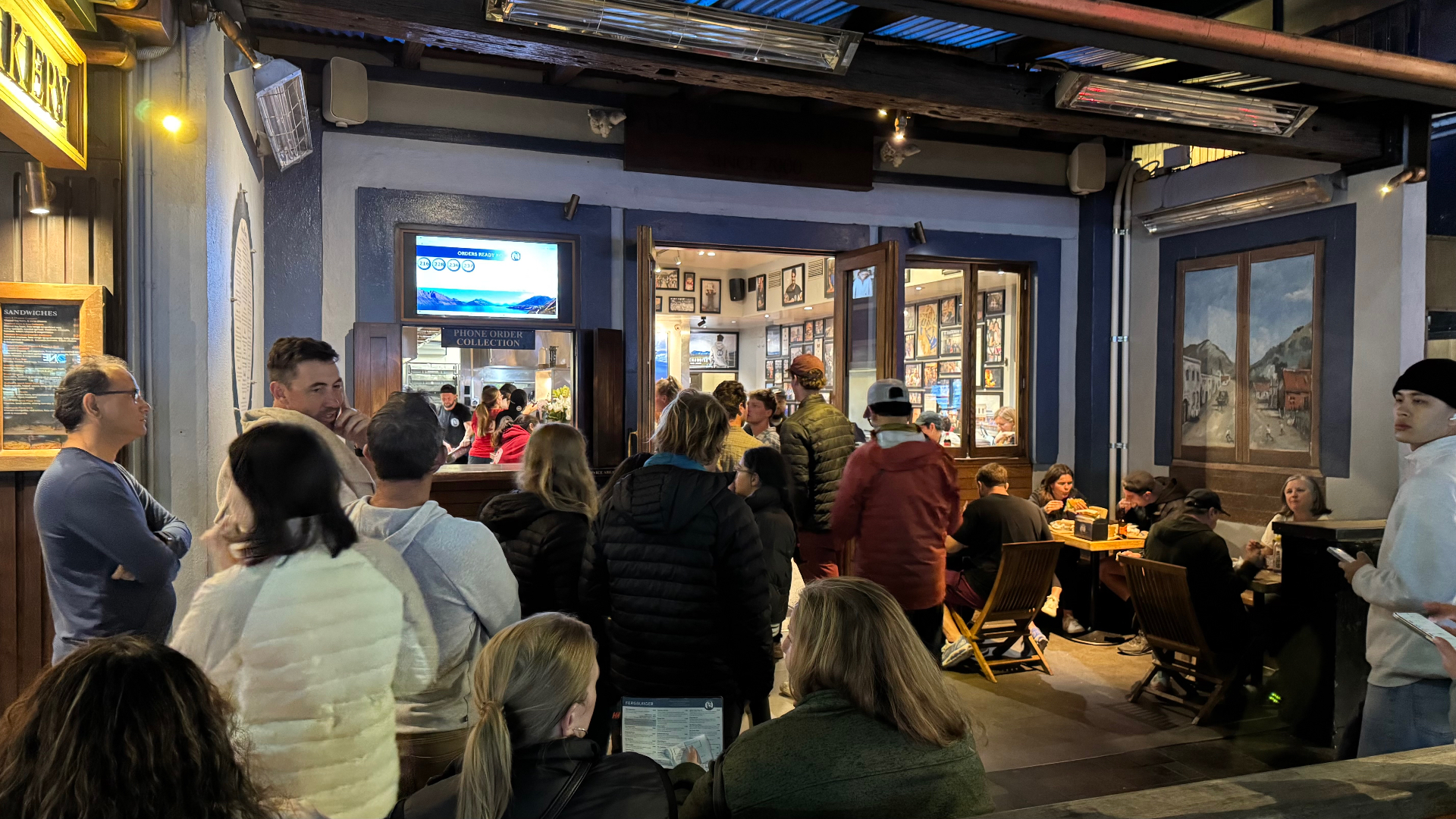 The busy interior of Fergburger at night, with customers gathered at the order collection window and outdoor seating
