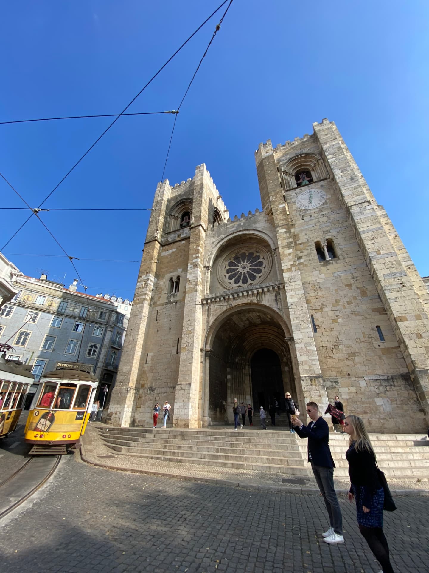 A yellow tram passing in front of Lisbon Cathedral