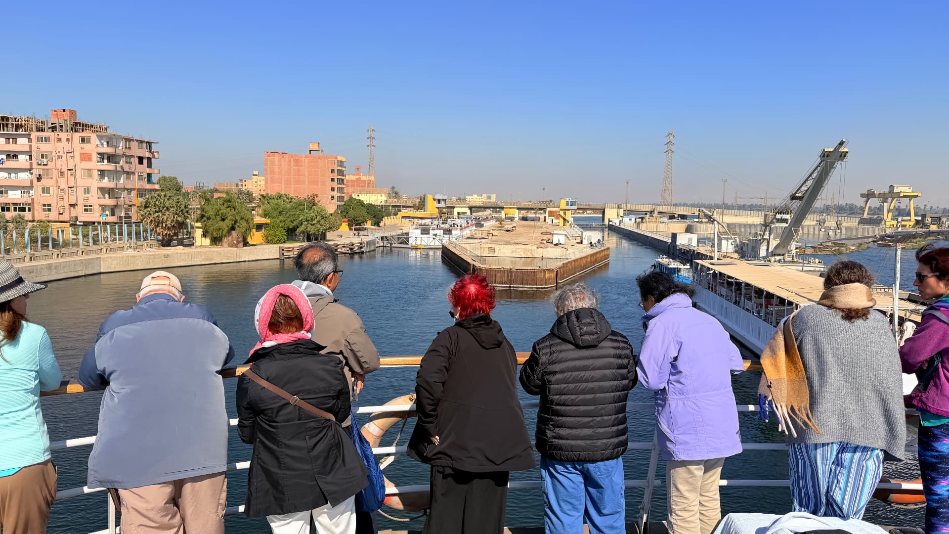 Passengers lining the rail of a cruise boat watching the approach to the Esna locks