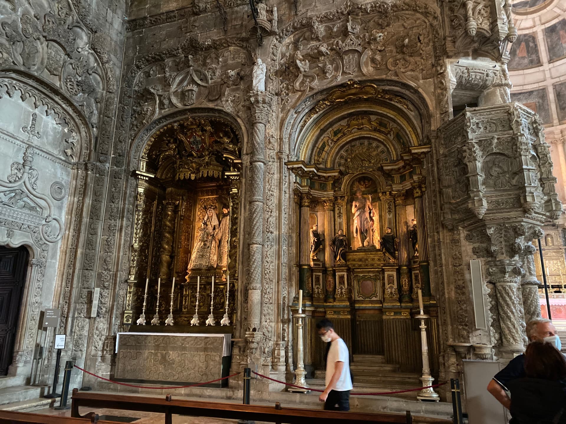 Gilded altars inside a Lisbon church with a few visitors