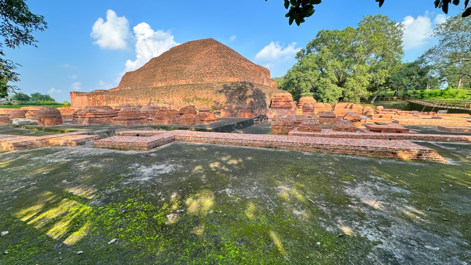 Sunlight falls across the large brick monument and its surrounding remains. — Nalanda, Bihar, India · Patna chapter.