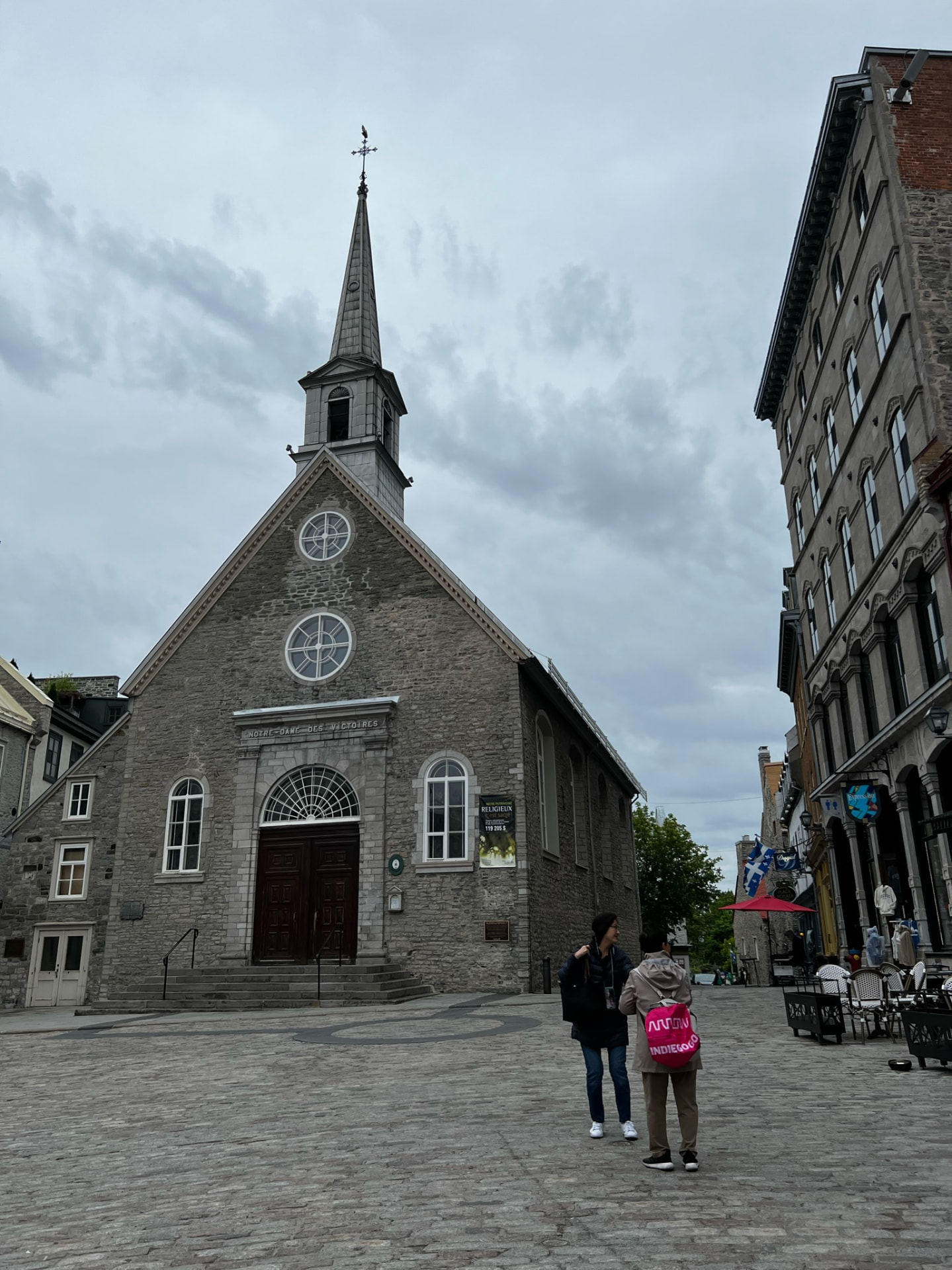 Stone church with a tall spire on a cobbled square