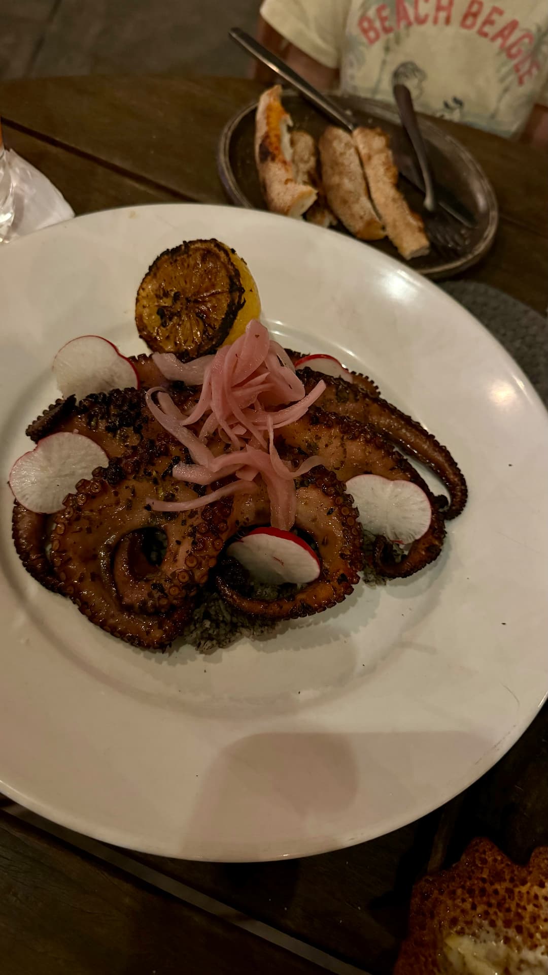 Grilled octopus served with radishes, pickled onions, and charred lemon