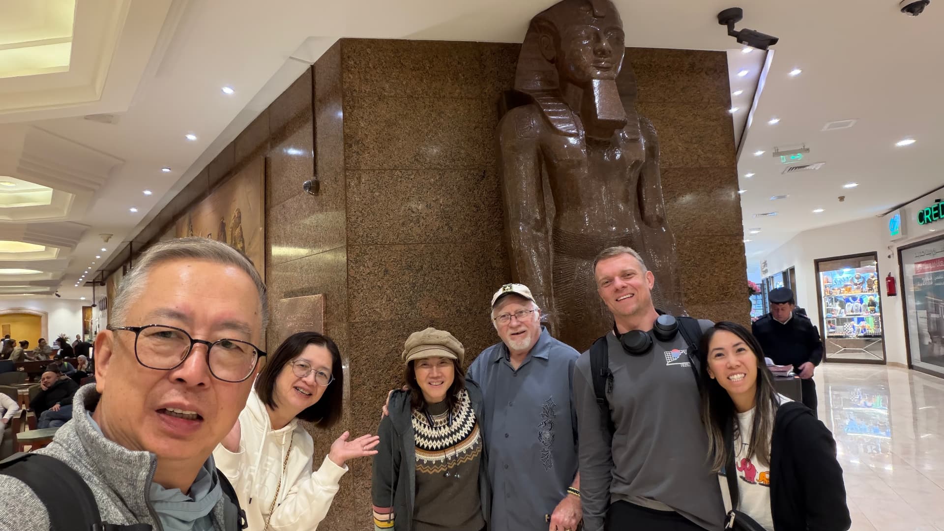 Our travel group posing for a photo beside a large granite pharaoh statue in a hall