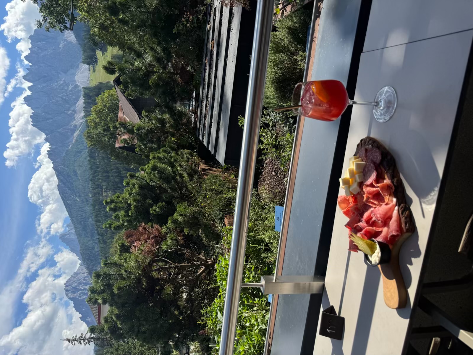 An Italian aperitivo of cured meats, cheese, and a red drink overlooking the Dolomites