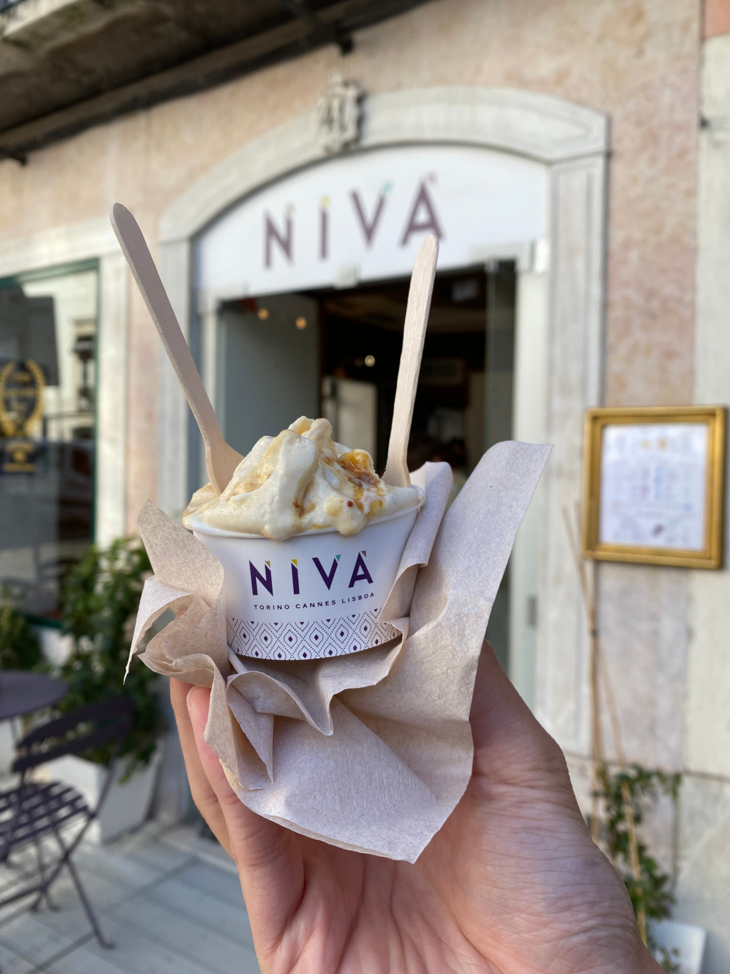 A hand holding a cup of gelato from the Niva shop