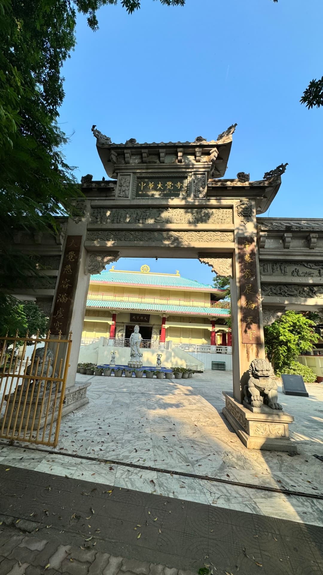 An ornate monastery gateway frames the courtyard beyond. — Bodh Gaya, Bihar, India.