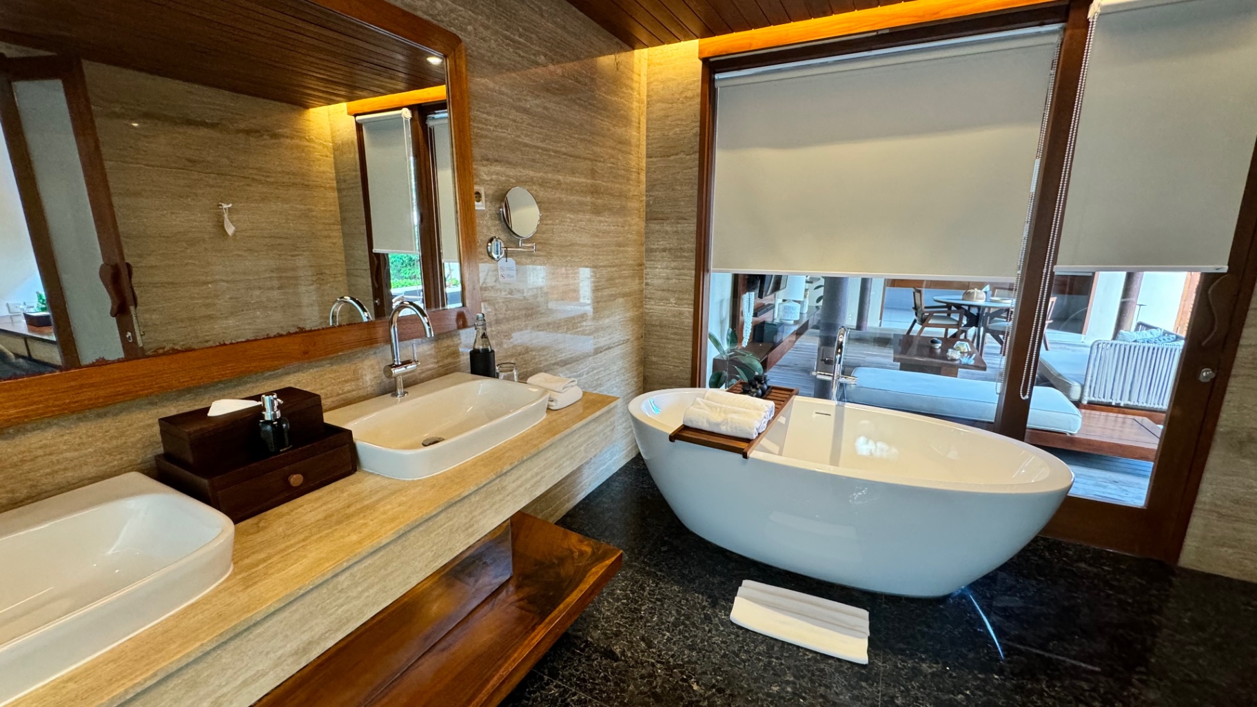 Villa bathroom with twin stone basins, a freestanding tub and garden view