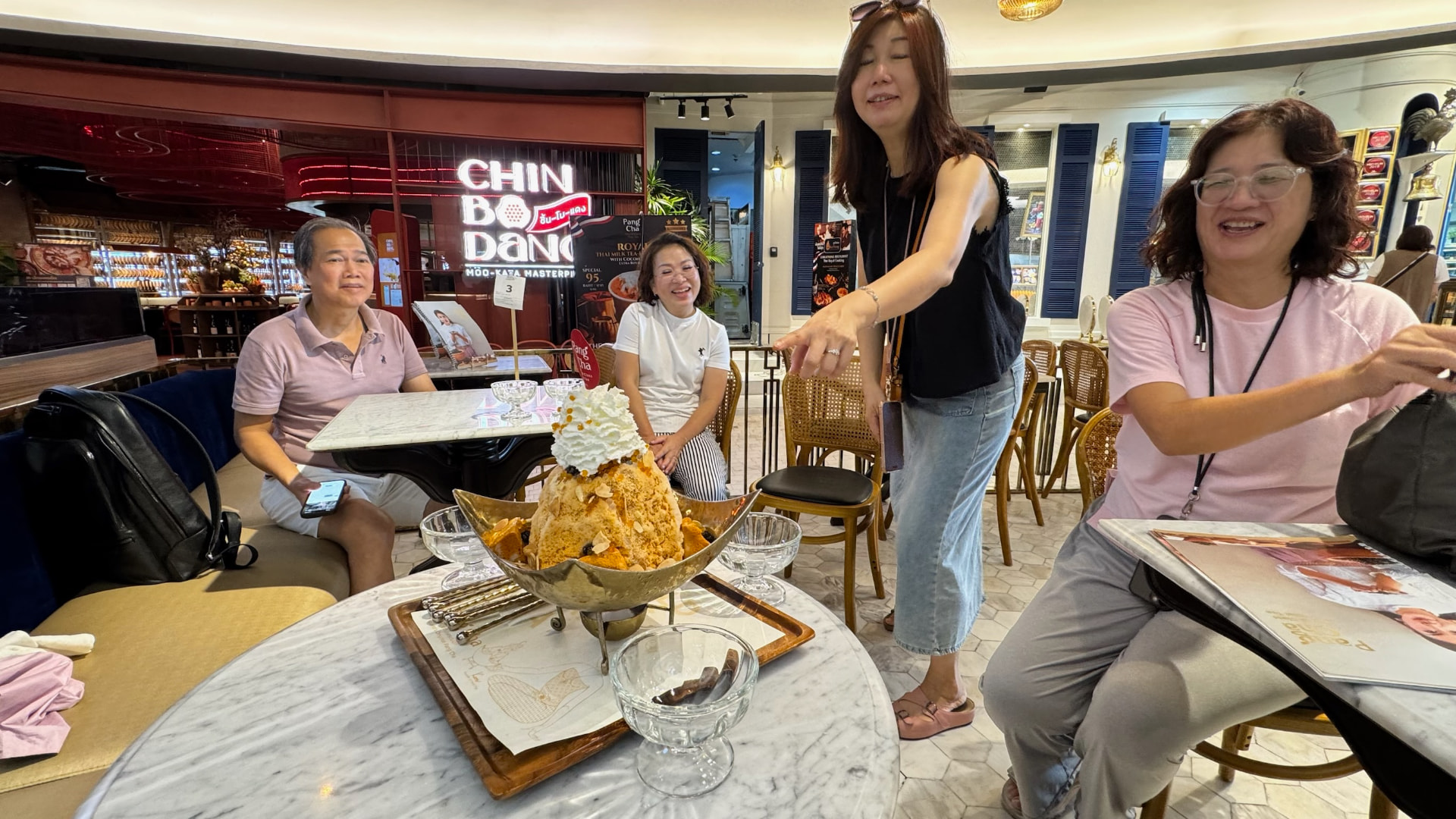 Friends gathered around a towering Thai shaved-ice dessert