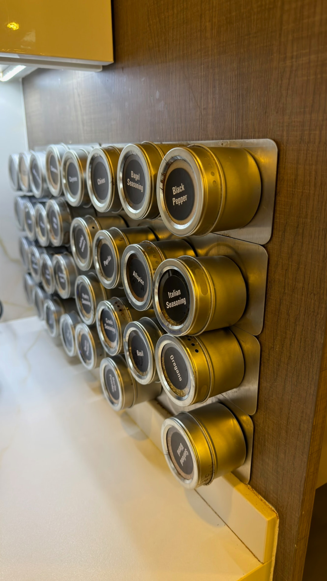 A wall-mounted collection of labeled spice tins