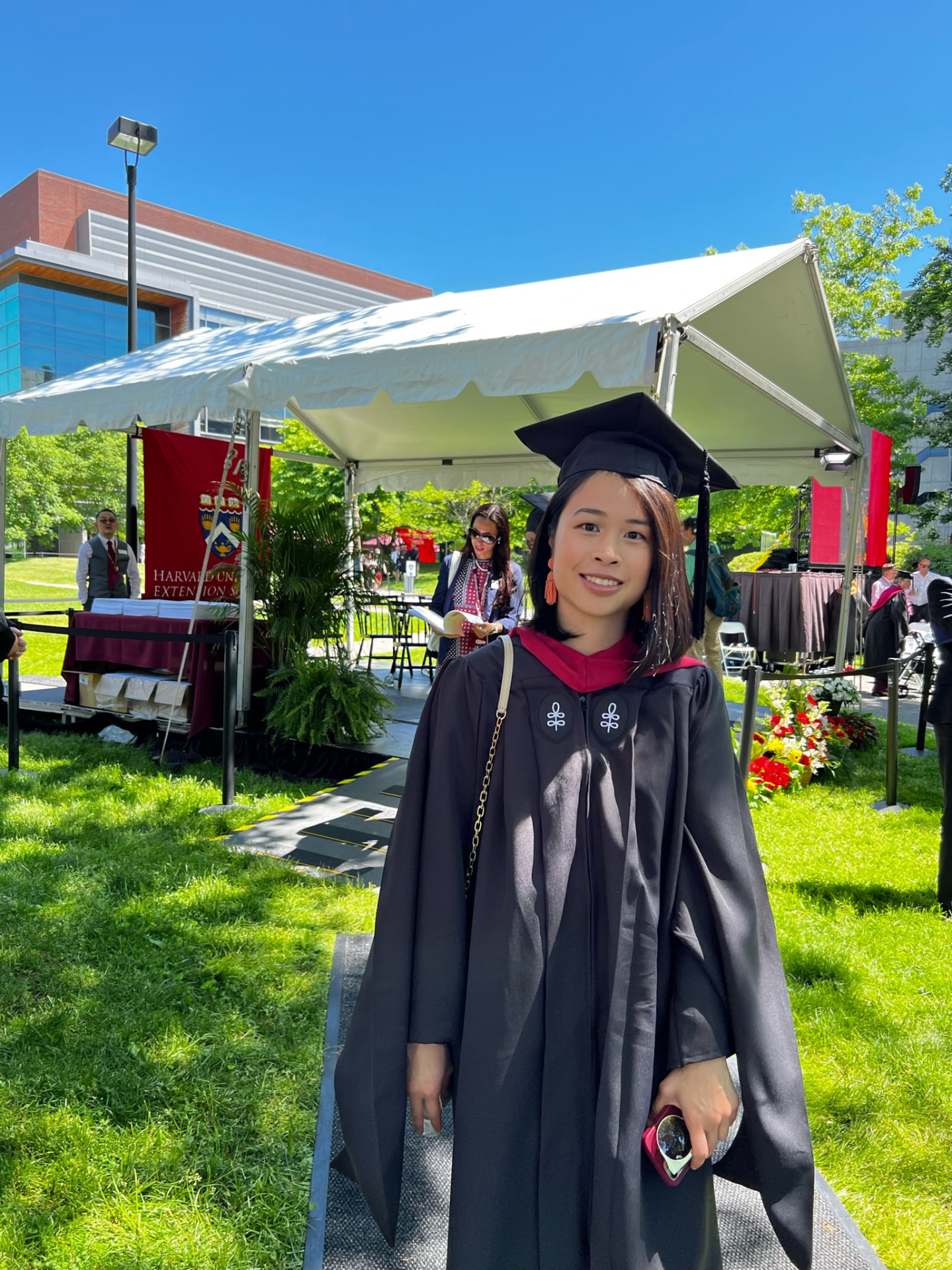 Jocelyn in cap and gown in front of the commencement stage tent