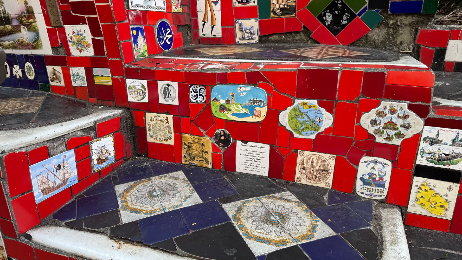Close view of red mosaic steps inset with illustrated tiles from many places