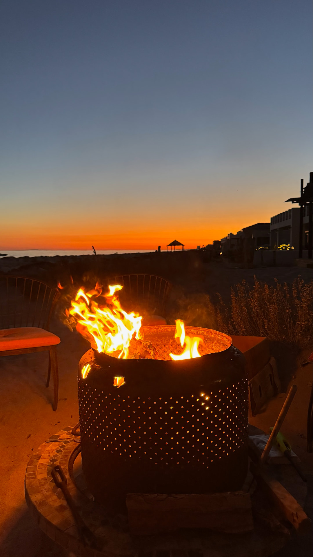 Beach fire glowing against an orange sunset