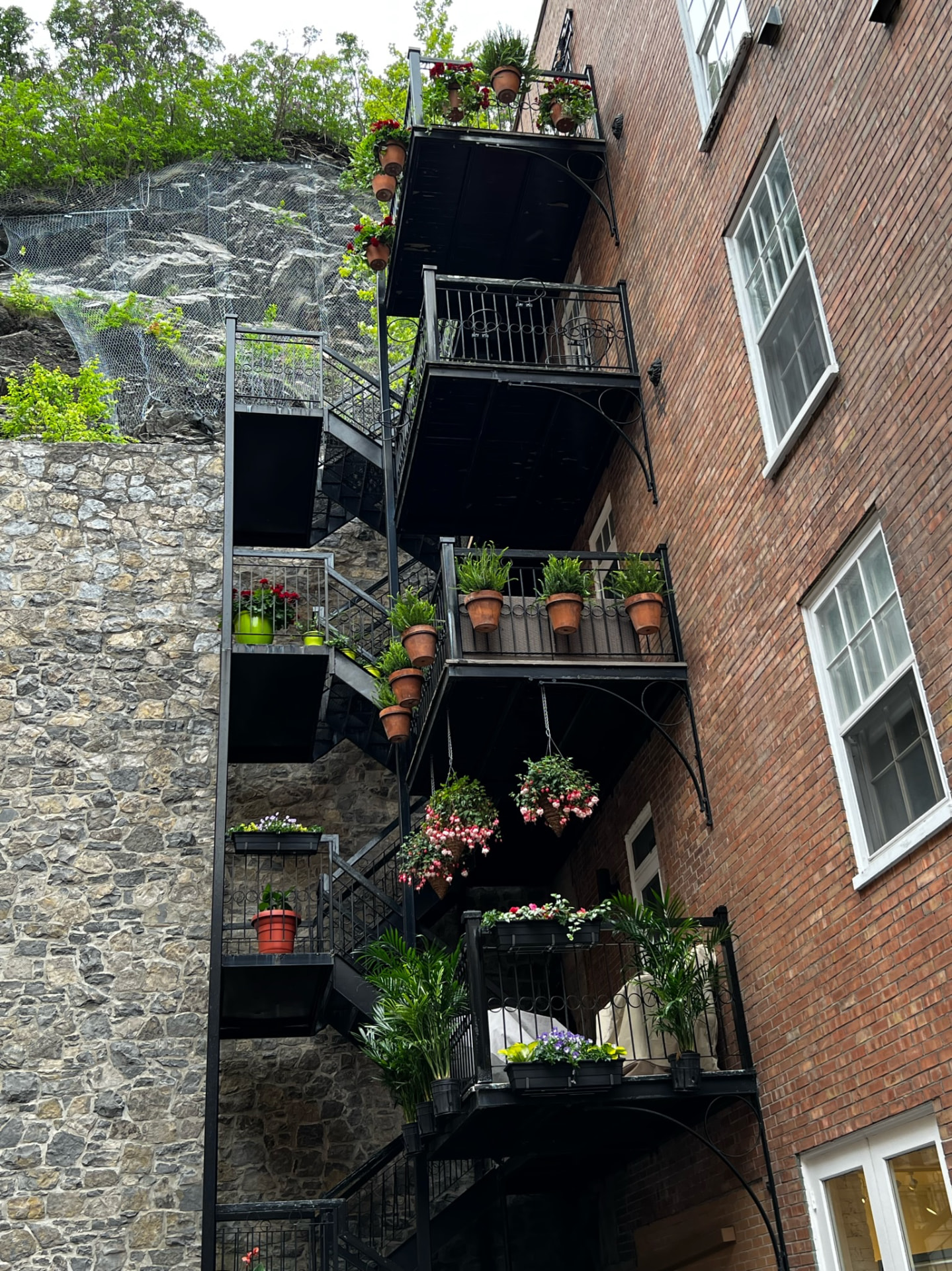 Flower-filled wrought iron balconies against brick and stone walls